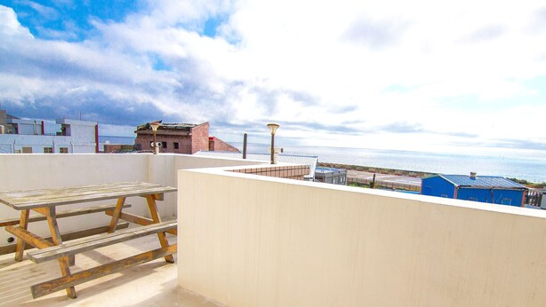 Una terraza en la azotea con vistas al mar, una mesa de madera y un farol.
