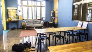 Una habitación con una mesa de madera, sillas negras, un sofá gris y un perro acostado en el suelo.