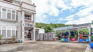 Un edificio con fachada de tejas, un espacio exterior cubierto con unidades de almacenamiento y un letrero con caracteres japoneses.