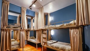Un dormitorio con literas, cortinas y suelo de madera.