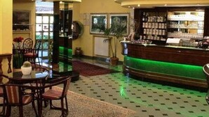 Eine Lobby mit einer Rezeption, einem Essbereich mit Stühlen und einem Tisch sowie einem gemusterten Boden.
