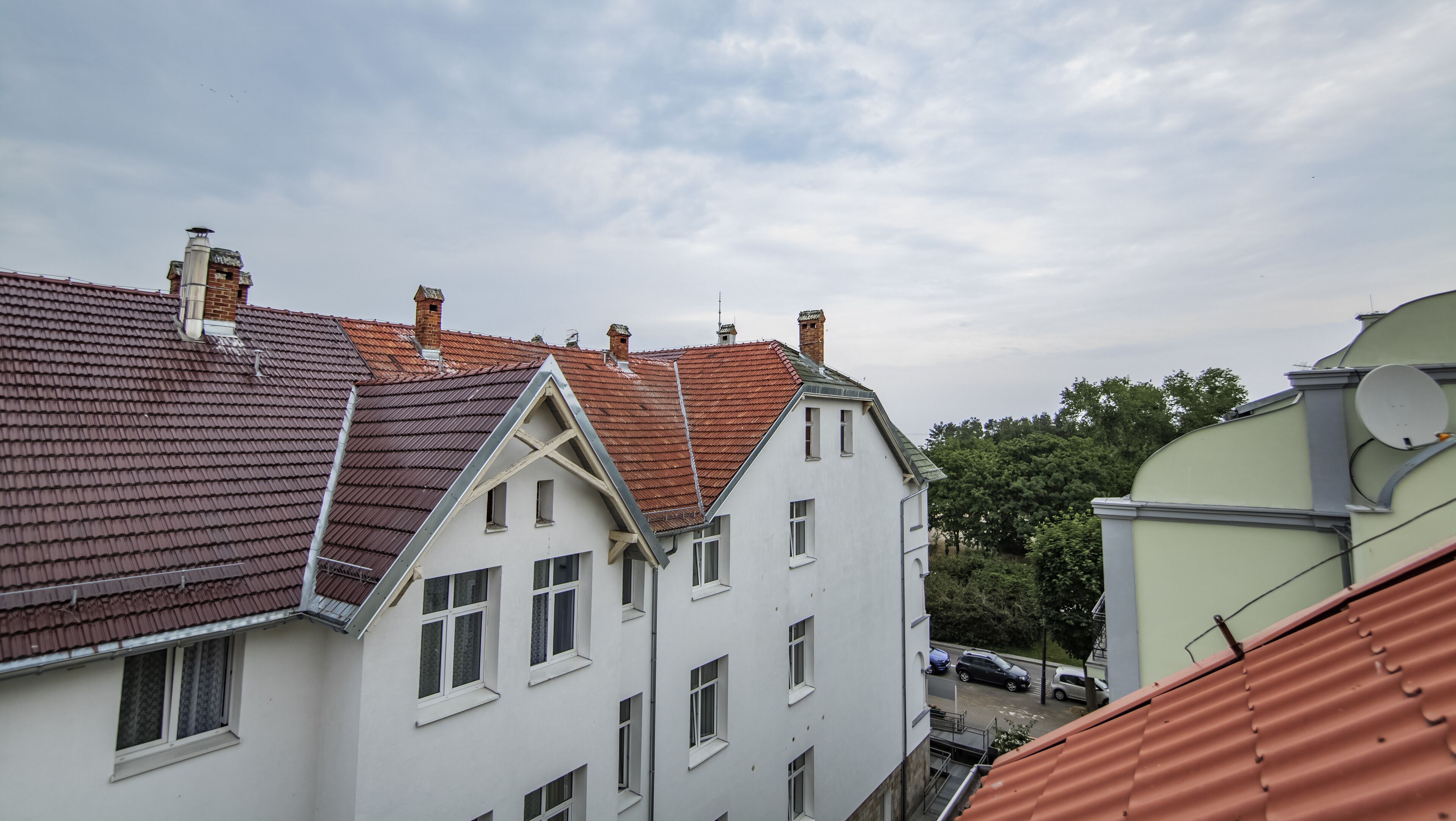 A row of white buildings with red-tiled roofs and multiple chimneys.