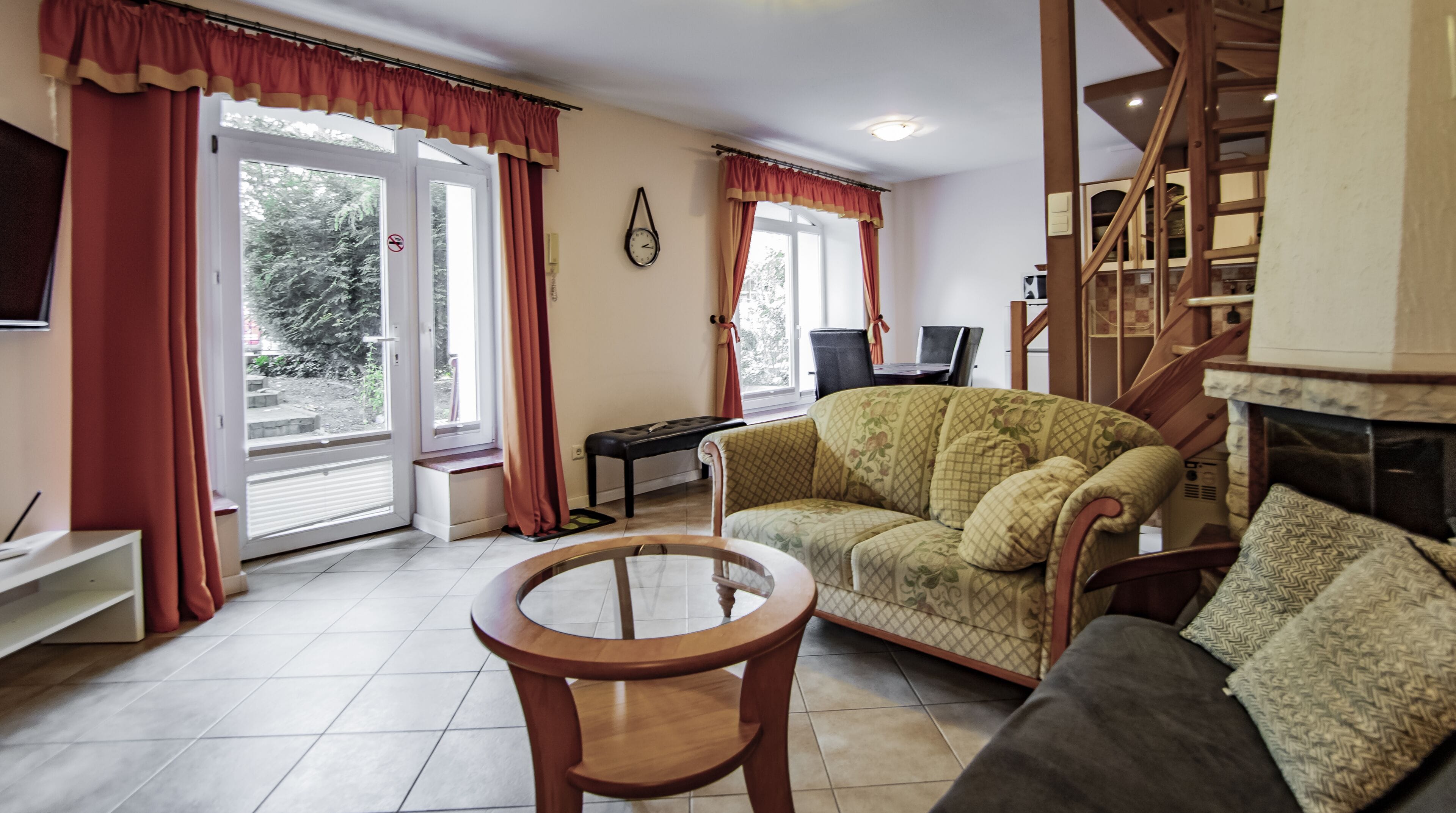 A living room with a sofa, a round wooden table, a bench, and a staircase.