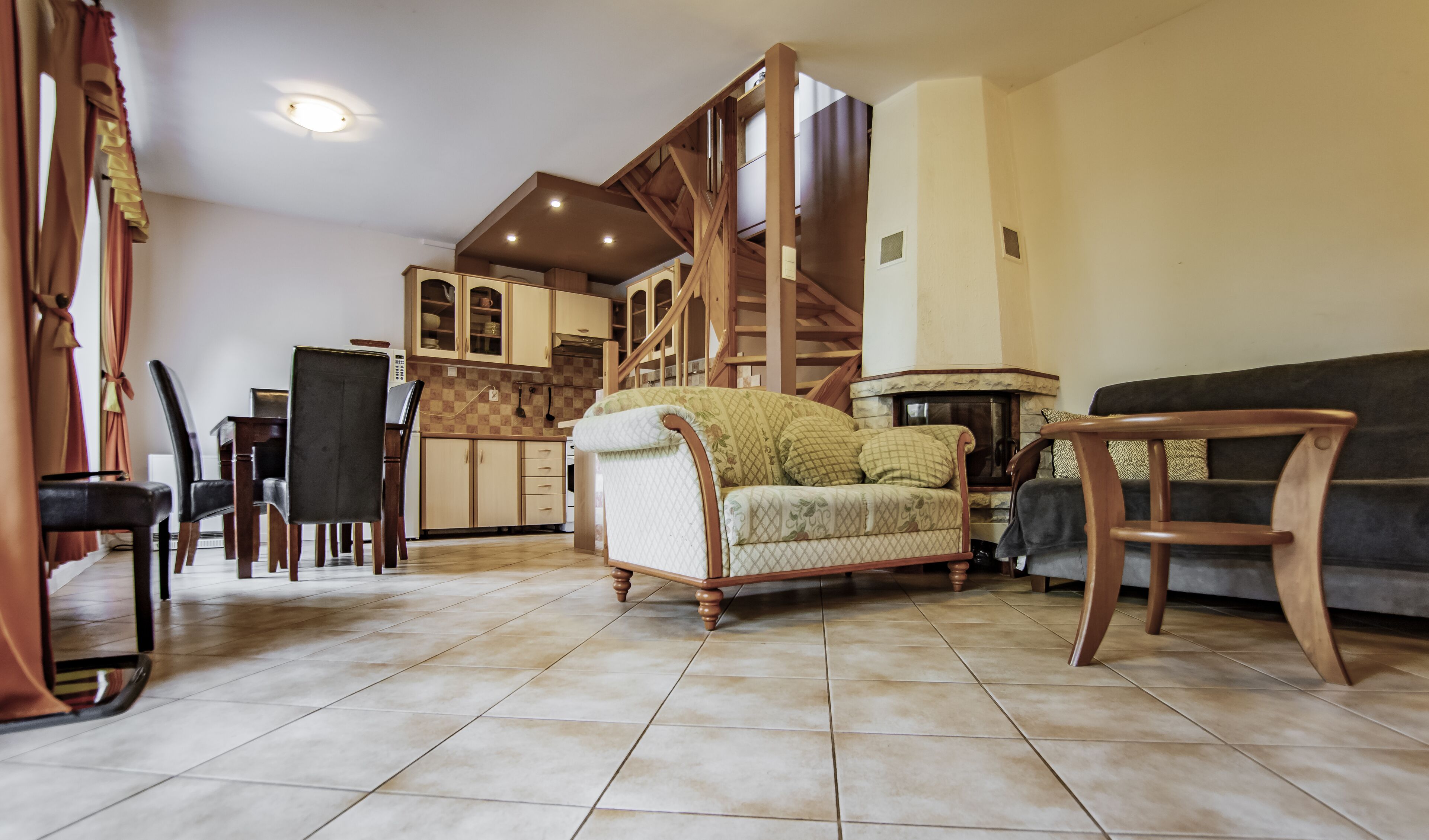 A spacious living area with a high ceiling, wooden staircase, and a fireplace.