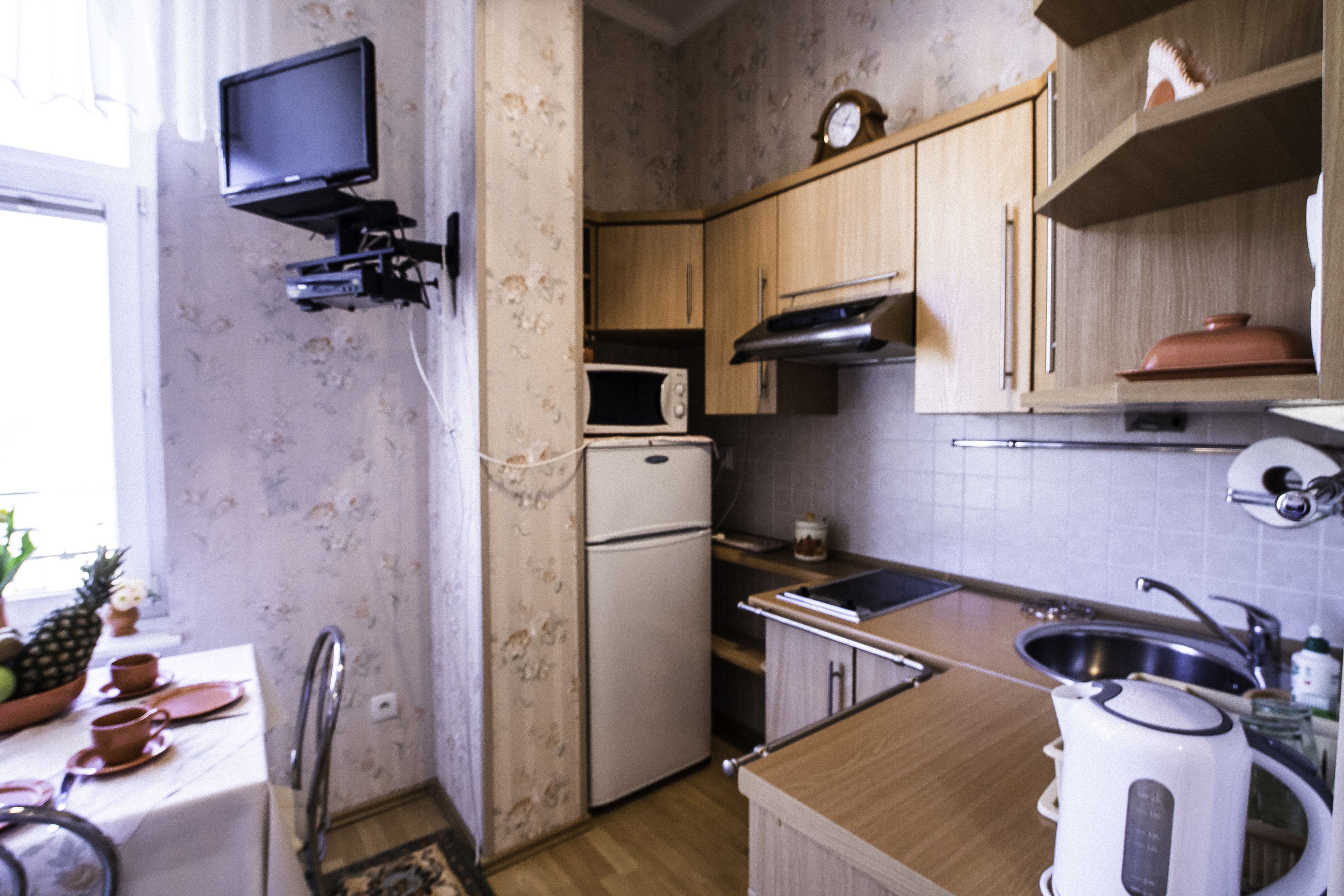 Une cuisine équipée de meubles en bois, d’un four à micro-ondes, d’un réfrigérateur, d’un évier et d’une bouilloire.