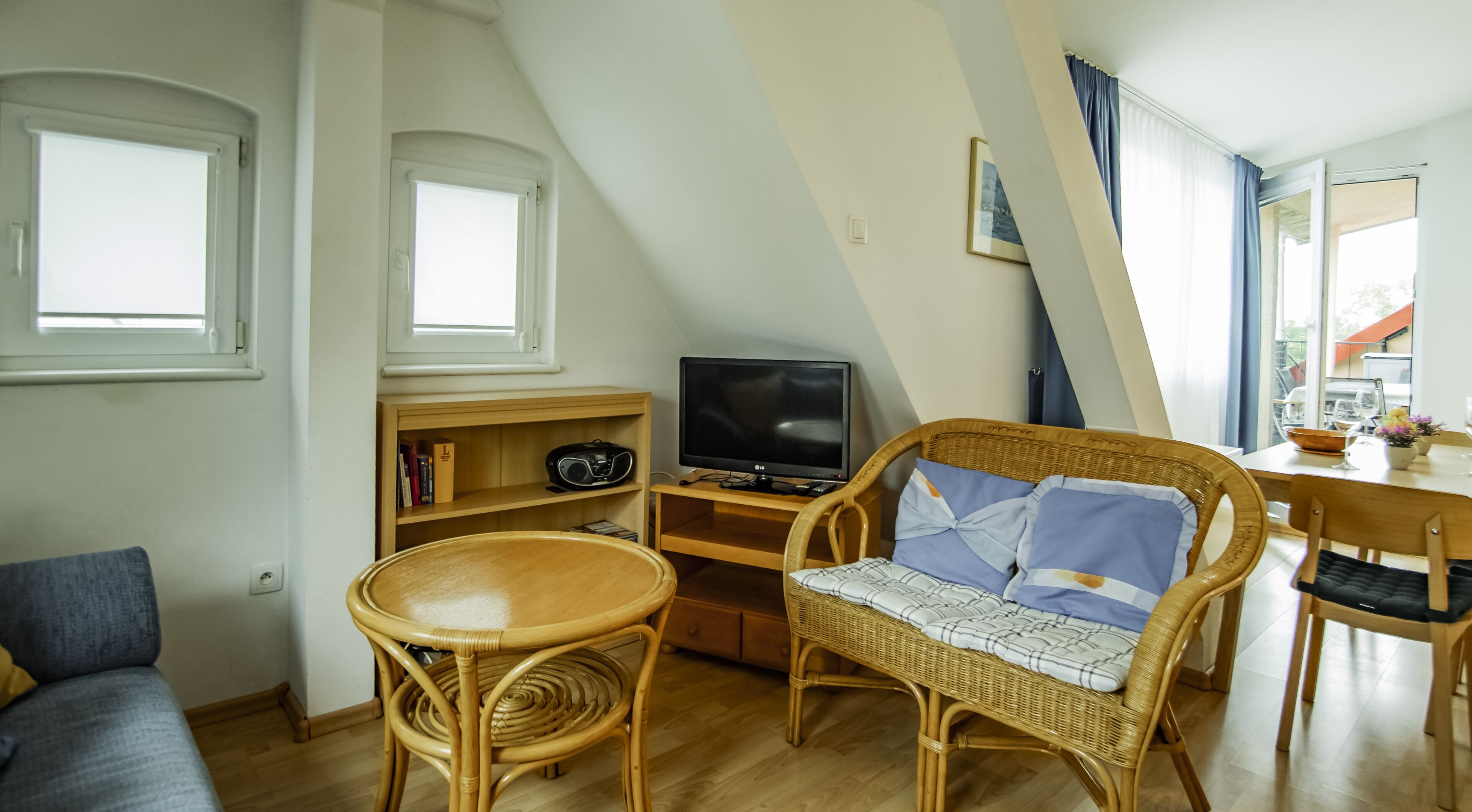 A cozy room with a television, wicker furniture, and a dining area.