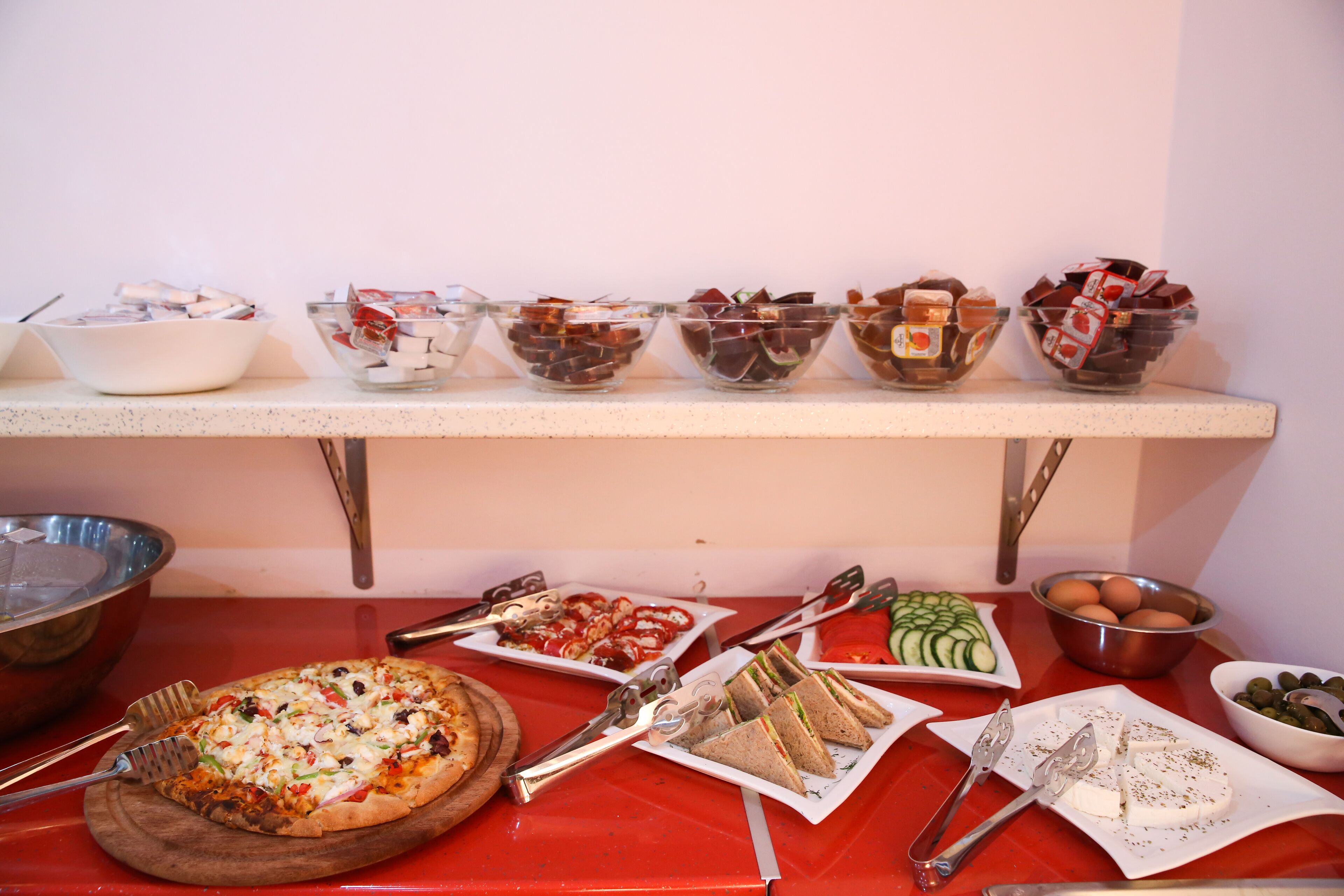A buffet table with various food items including a pizza, sandwiches, and a variety of snacks.
