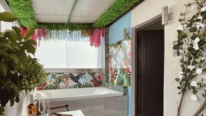 A modern bathroom with a large bathtub, a window with a floral view, and a dining area with a table and chairs. - Athens Starlight Hotel (Athens)