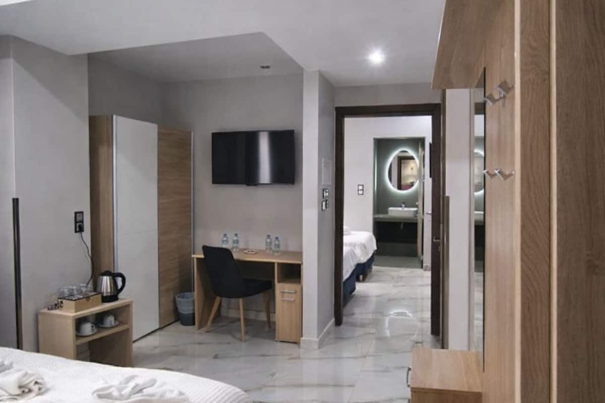 A modern hotel room with a bed, desk, and a television.