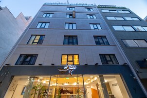 A modern hotel building with a prominent 'Athena Light Star' sign, large windows, and a reception area visible through the glass facade.