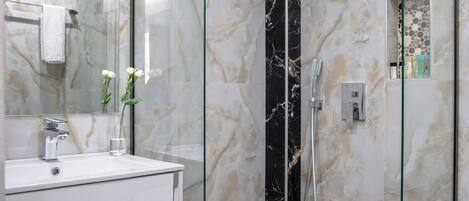 A modern bathroom with a glass-enclosed shower, a white sink, and a mirror.