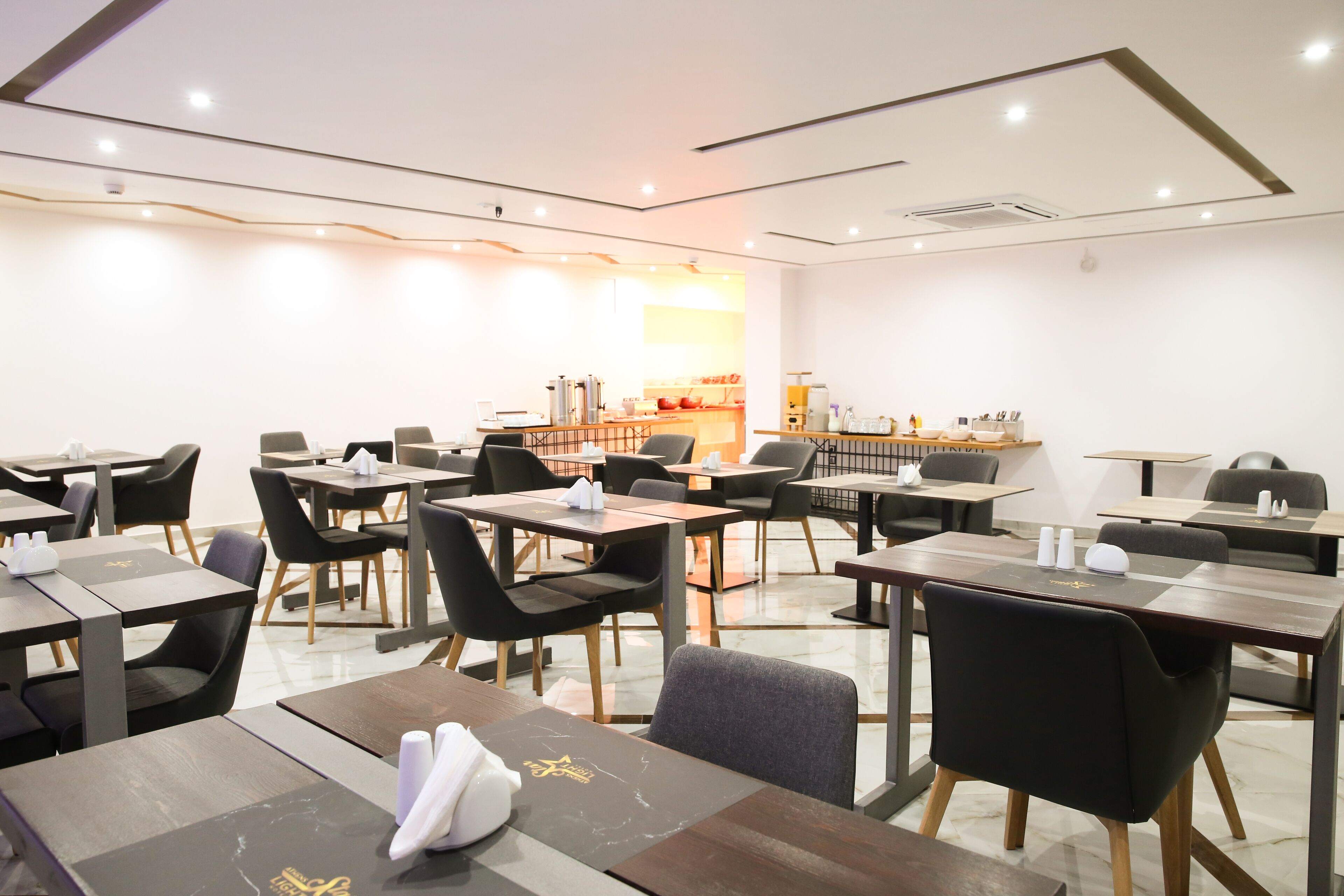 A modern restaurant with multiple tables and chairs, a counter with a menu, and a clean, well-lit interior.