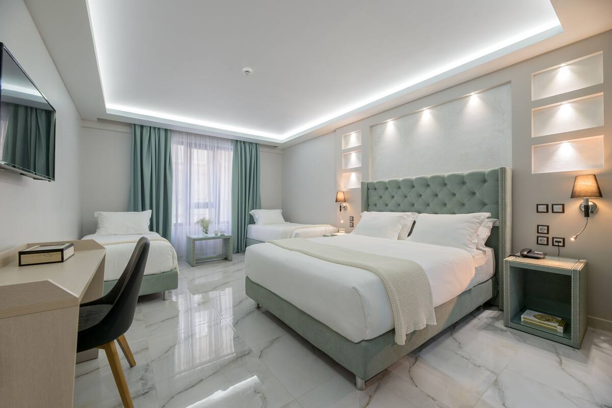 A modern hotel room with a large bed, two bedside tables, a desk, and a chair.