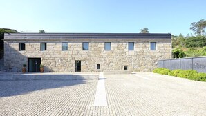 A stone building with a flat roof, a central entrance, and a paved courtyard. - Quinta das Lavandeiras - Caldas de Vizela (Vizela)