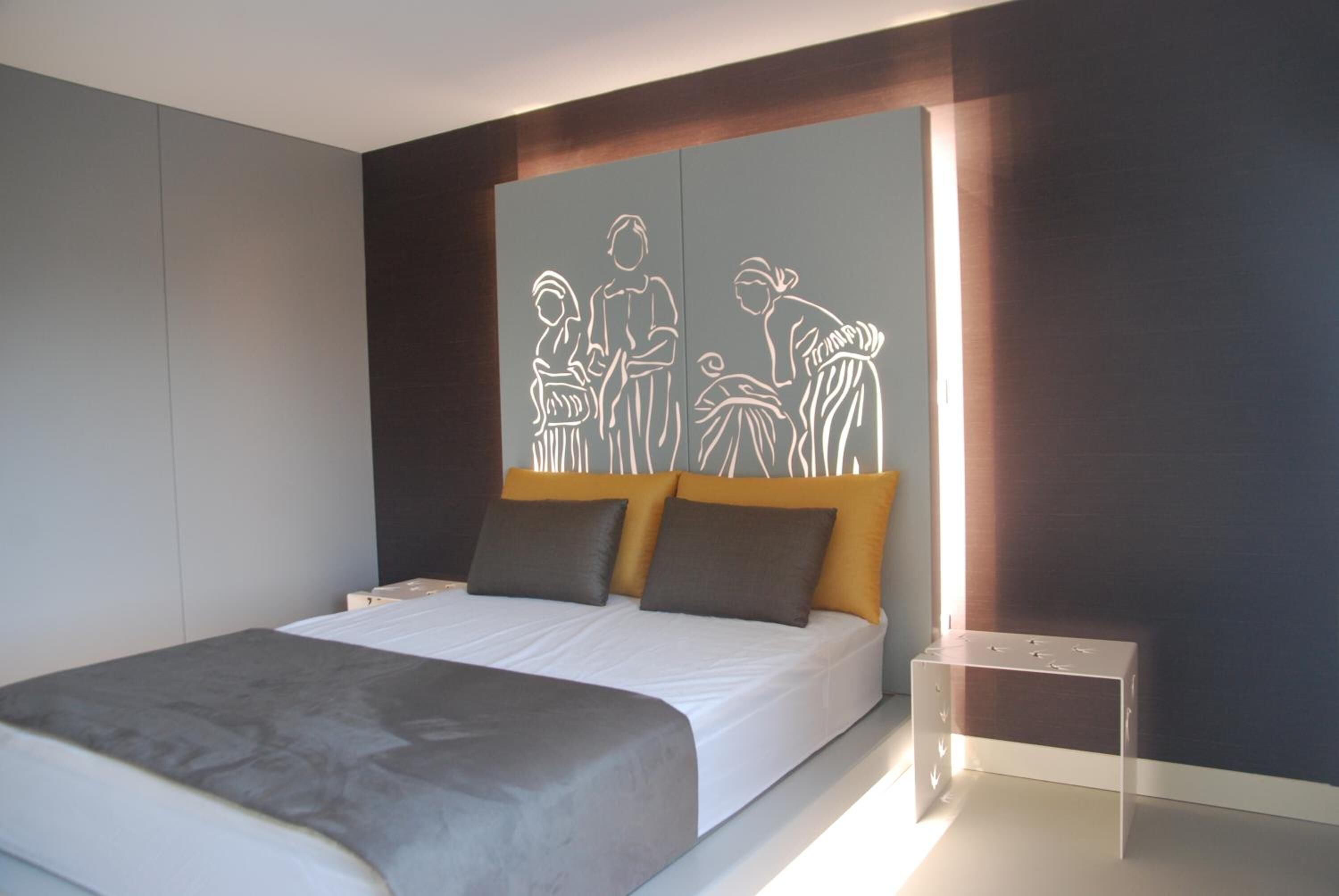 Een moderne slaapkamer met een groot bed, een hoofdbord met een wit silhouetontwerp, en een nachtkastje.