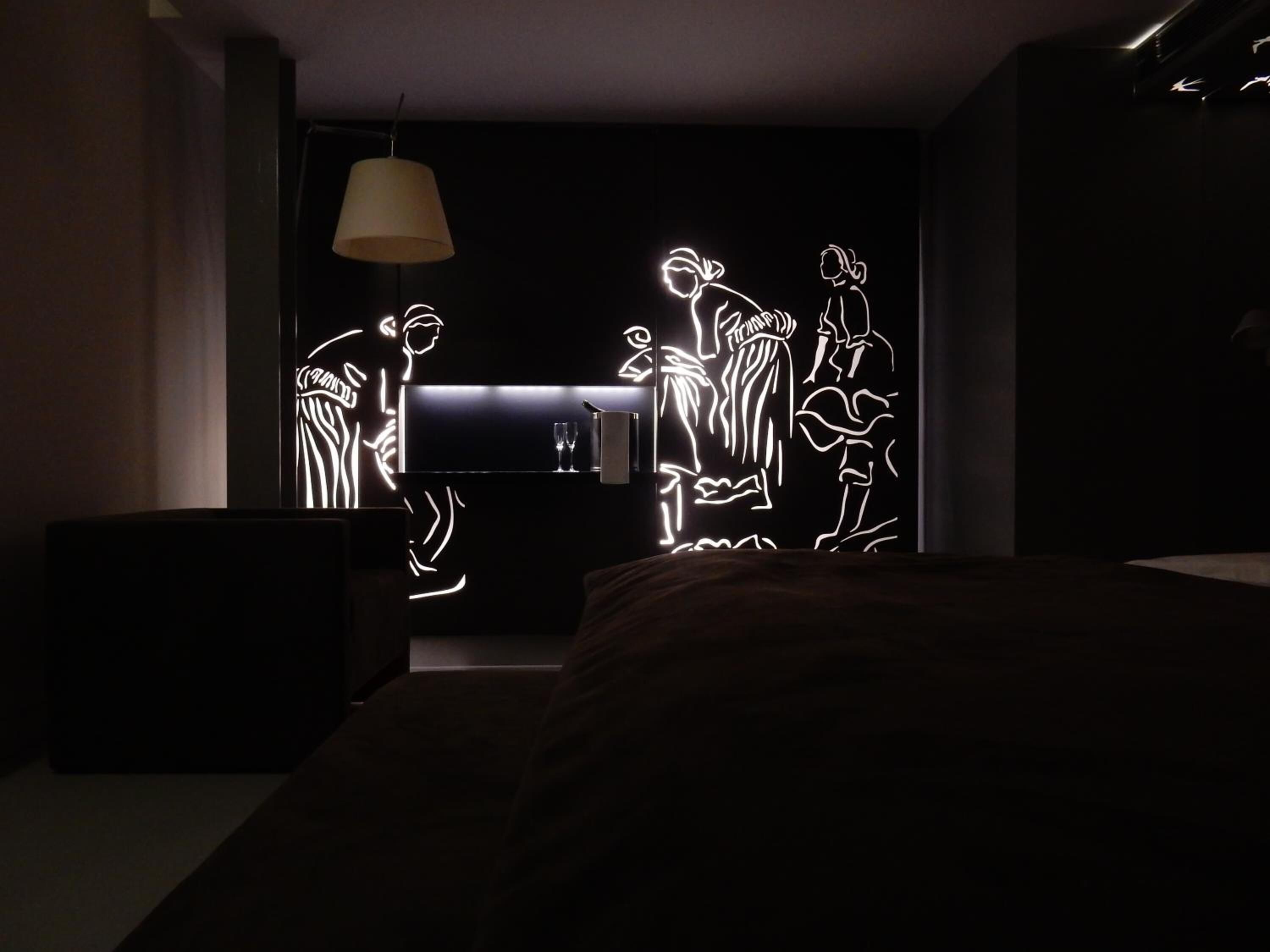 Un dormitorio moderno con cama, mesita de noche y lámpara de pared.