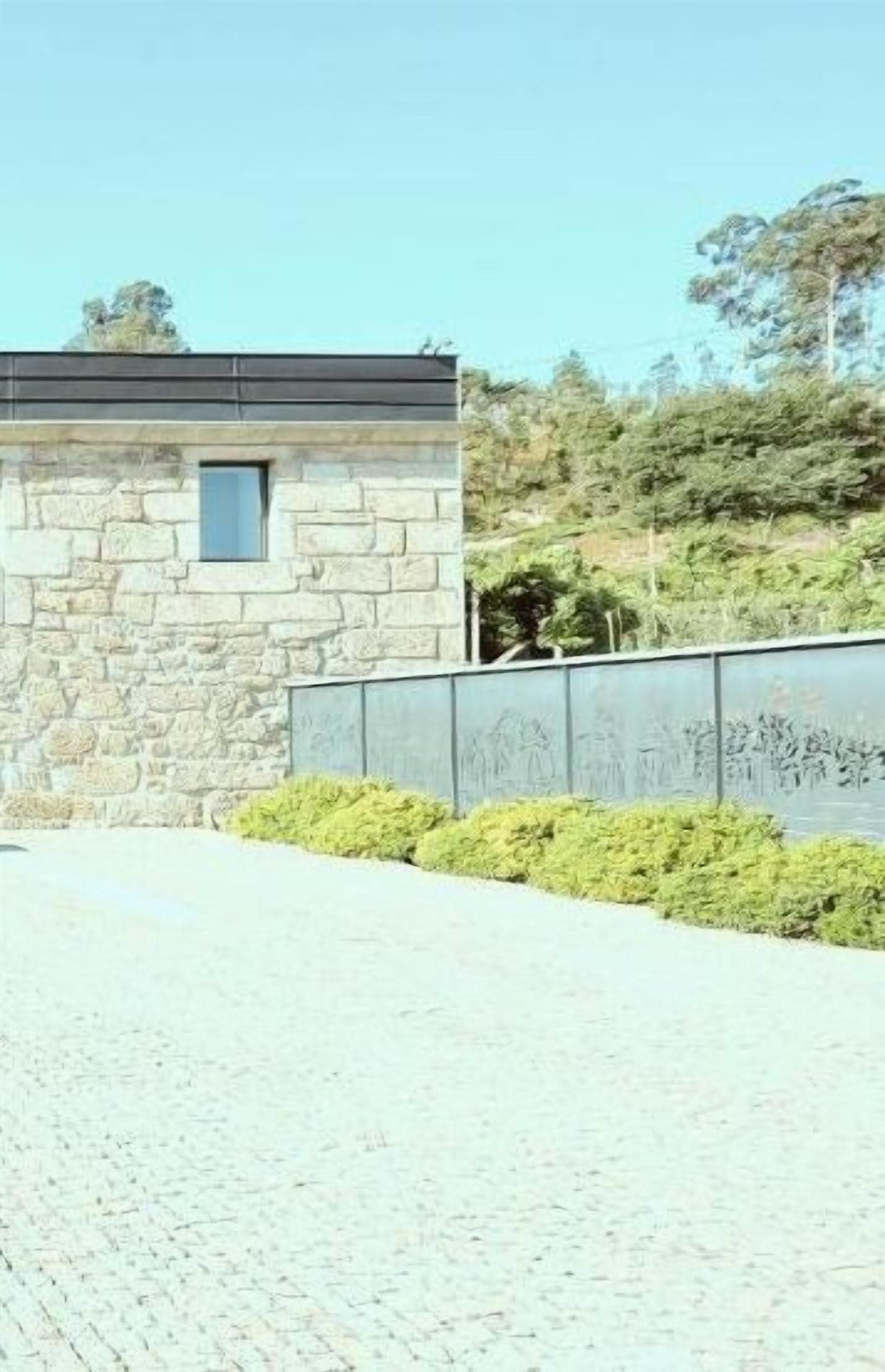 Um edifício de pedra com uma pequena janela e um espaço pavimentado na frente.