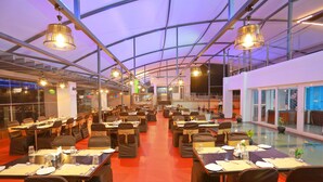Een ruim restaurant met meerdere eettafels, stoelen en hangende吊灯.