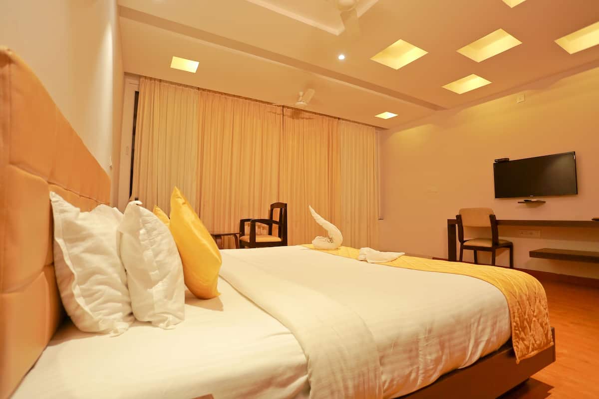 Una habitación de hotel con una cama grande, un televisor de pantalla plana montado en la pared y un ventilador de techo.