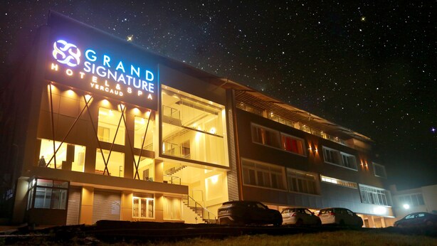 Een hotel met een modern design, met een opvallend bord waarop staat 'GRAND SIGNATURE HOTEL & SPA'.