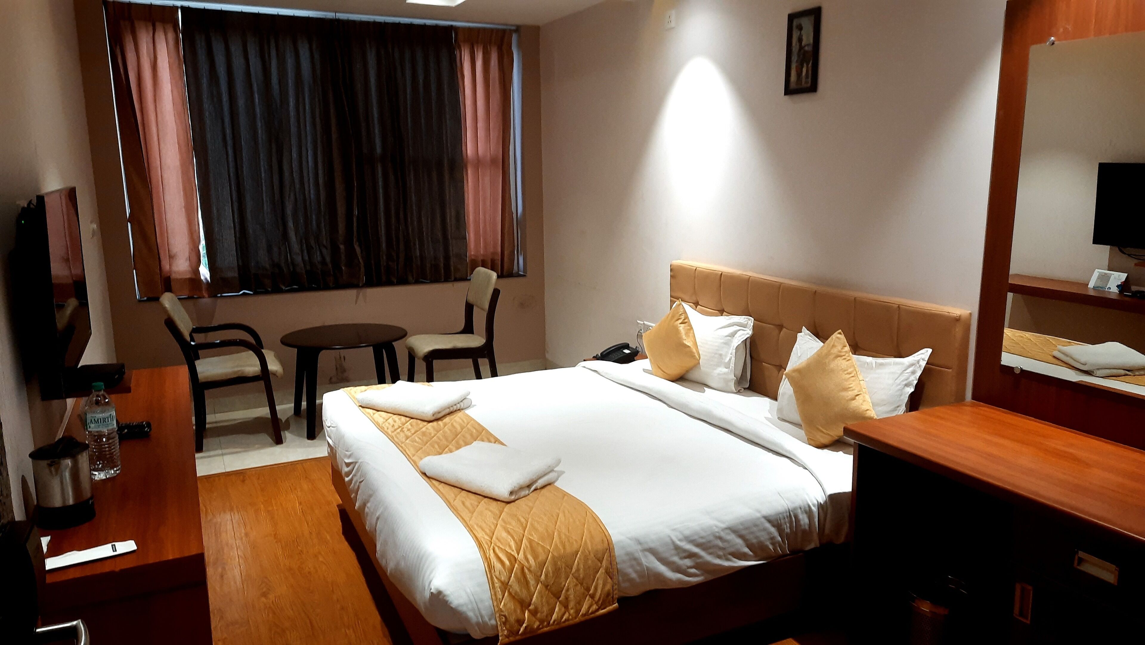 A hotel room with a bed, bedside table, chair, and a small table with a chair.