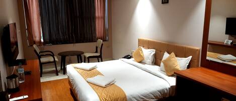 A hotel room with a bed, bedside table, chair, and a small table with a chair.