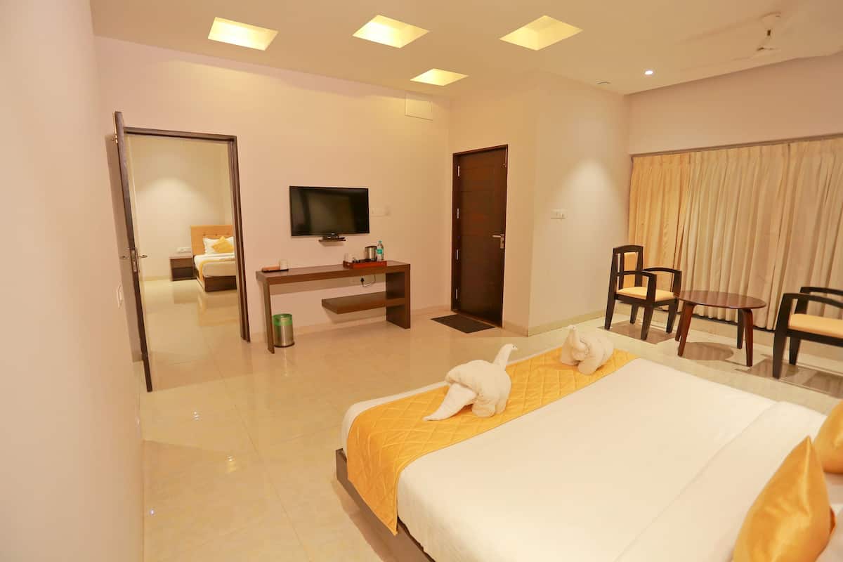 Una habitación de hotel con cama, escritorio, televisor y zona de estar con sillas y mesa.