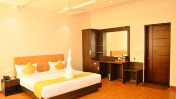 A hotel room with a large bed, a desk, a mirror, and a wardrobe.