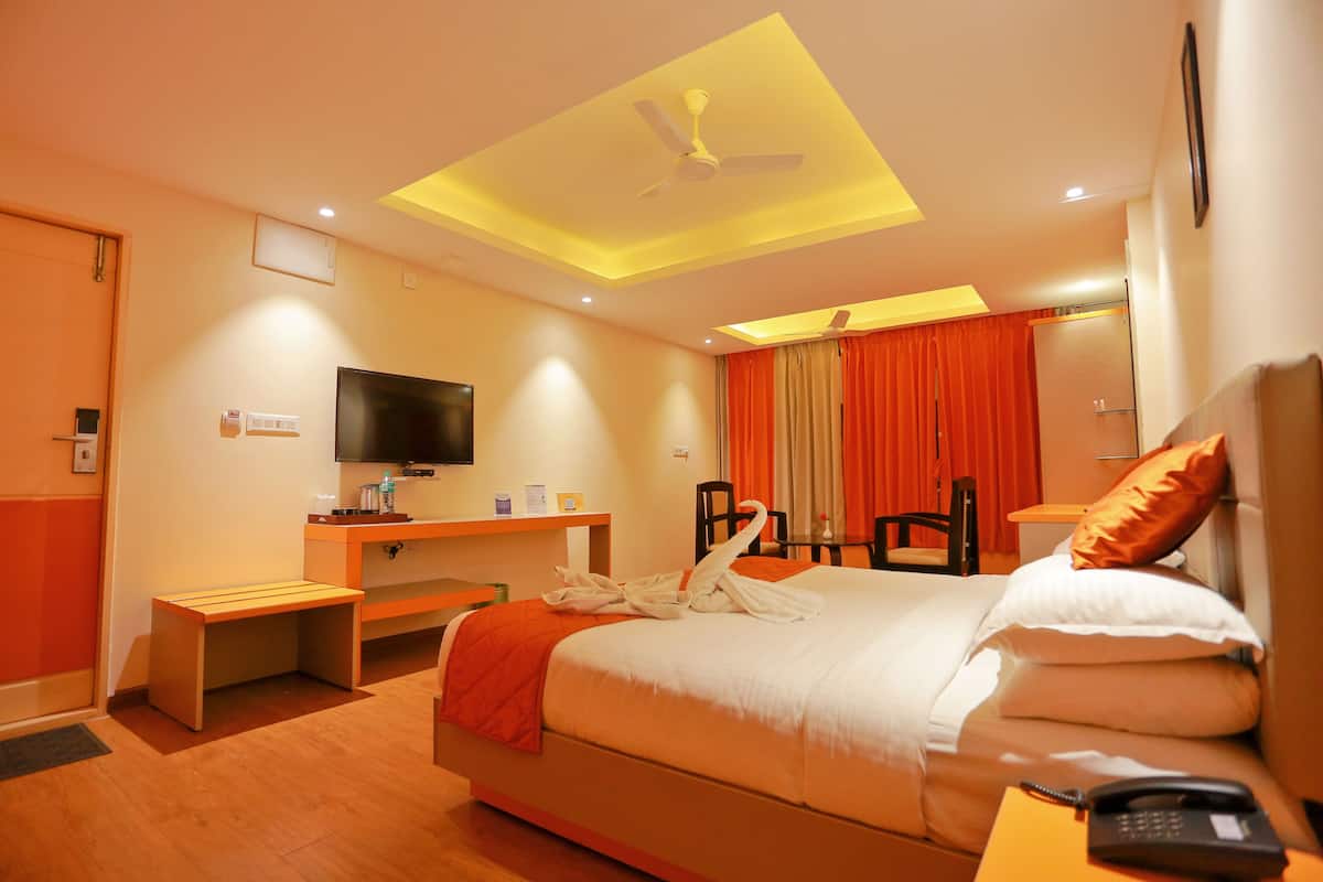 Una habitación de hotel con cama, escritorio, televisor y ventilador de techo.