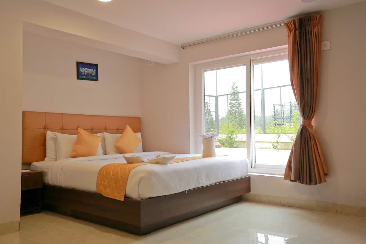 Un dormitorio moderno con una cama grande, una mesita de noche, una ventana con cortinas y vistas al exterior.