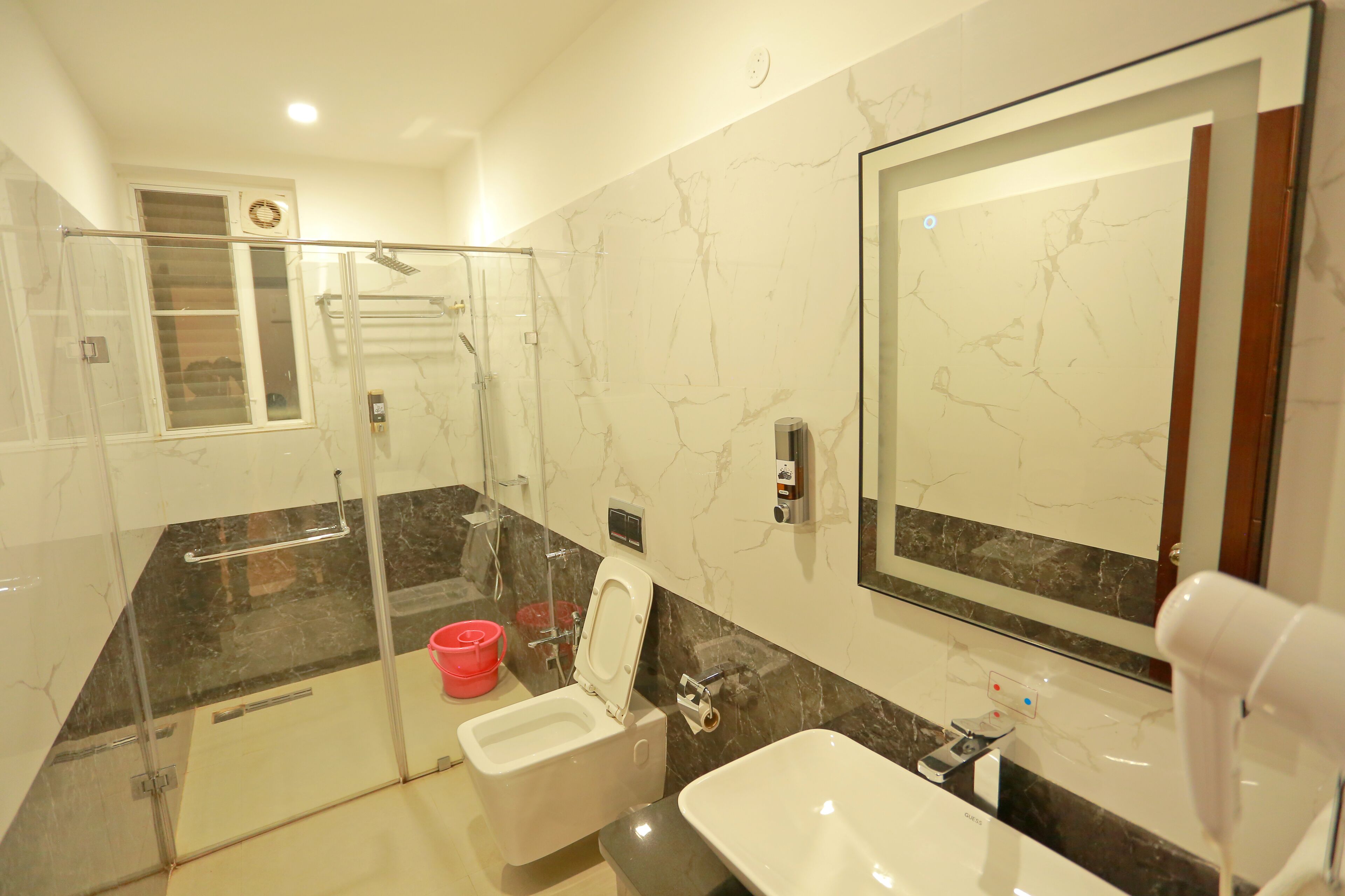 Un bagno moderno con cabina doccia in vetro, un WC, un lavandino e uno specchio grande.