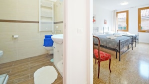 A bedroom with a bed, a chair, a window, and a bathroom with a toilet and sink. - DolceVita Apartments N. 372 (Venice)