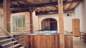 A wooden interior with a glass-enclosed pool, wooden stairs, and a wooden cabinet. - Romantik Hotel Zum Klosterbräu (Neuburg)
