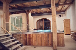 Una piscina techada, una piscina al aire libre, sombrillas