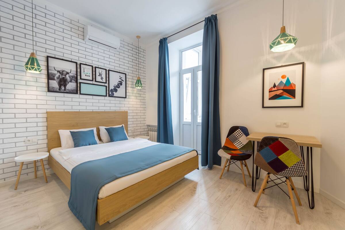 A modern bedroom with a wooden bed, a small desk, and chairs.
