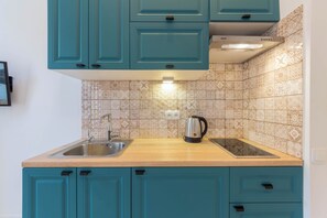 Een koelkast, een magnetron, een kookplaat, kookgerei, borden en bestek