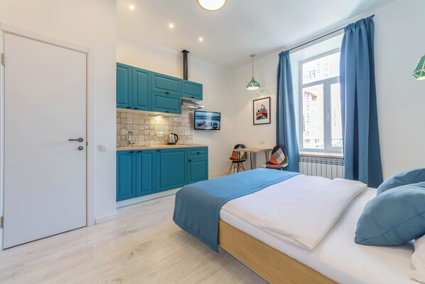 Une chambre avec un lit, un bureau et un coin cuisine.