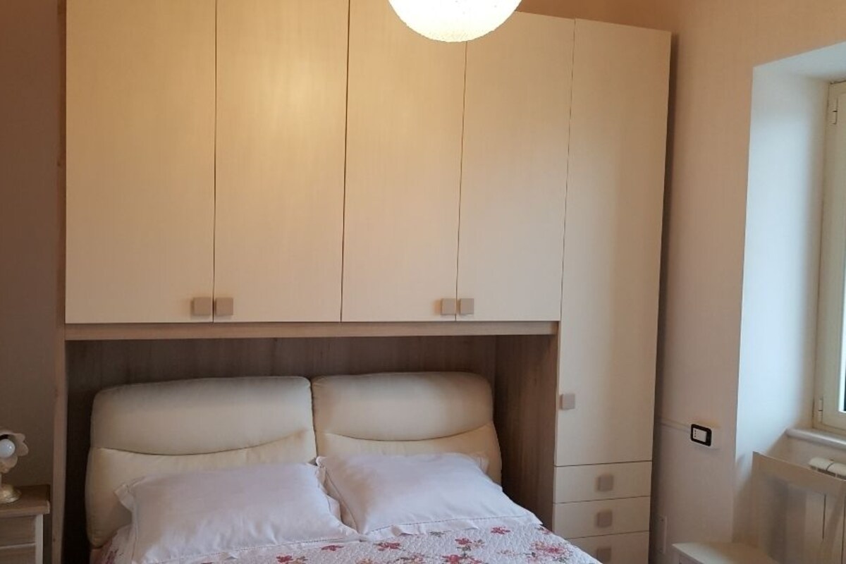 A bedroom with a bed, nightstands, and a wardrobe.