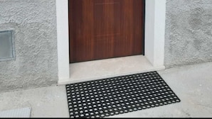 A wooden door with a glass panel and a brass handle, set in a beige and gray building facade. - Agata (Cocullo)