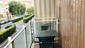 Ein Balkon mit Tisch und Stühlen, Blick auf die Straße und ein Gebäude mit einer Kachelwand.