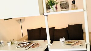Ein Zimmer mit einem Etagenbett, einem kleinen Tisch mit Zeitschriften, einer Lampe und einem Regal mit Dekoration.