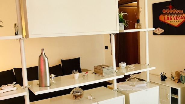 Ein Hotelzimmer mit Etagenbett, Schreibtisch inklusive Computer, einem kleinen Tisch mit Pflanze und einem Schild mit der Aufschrift 'Welcome to Las Vegas' an der Wand.
