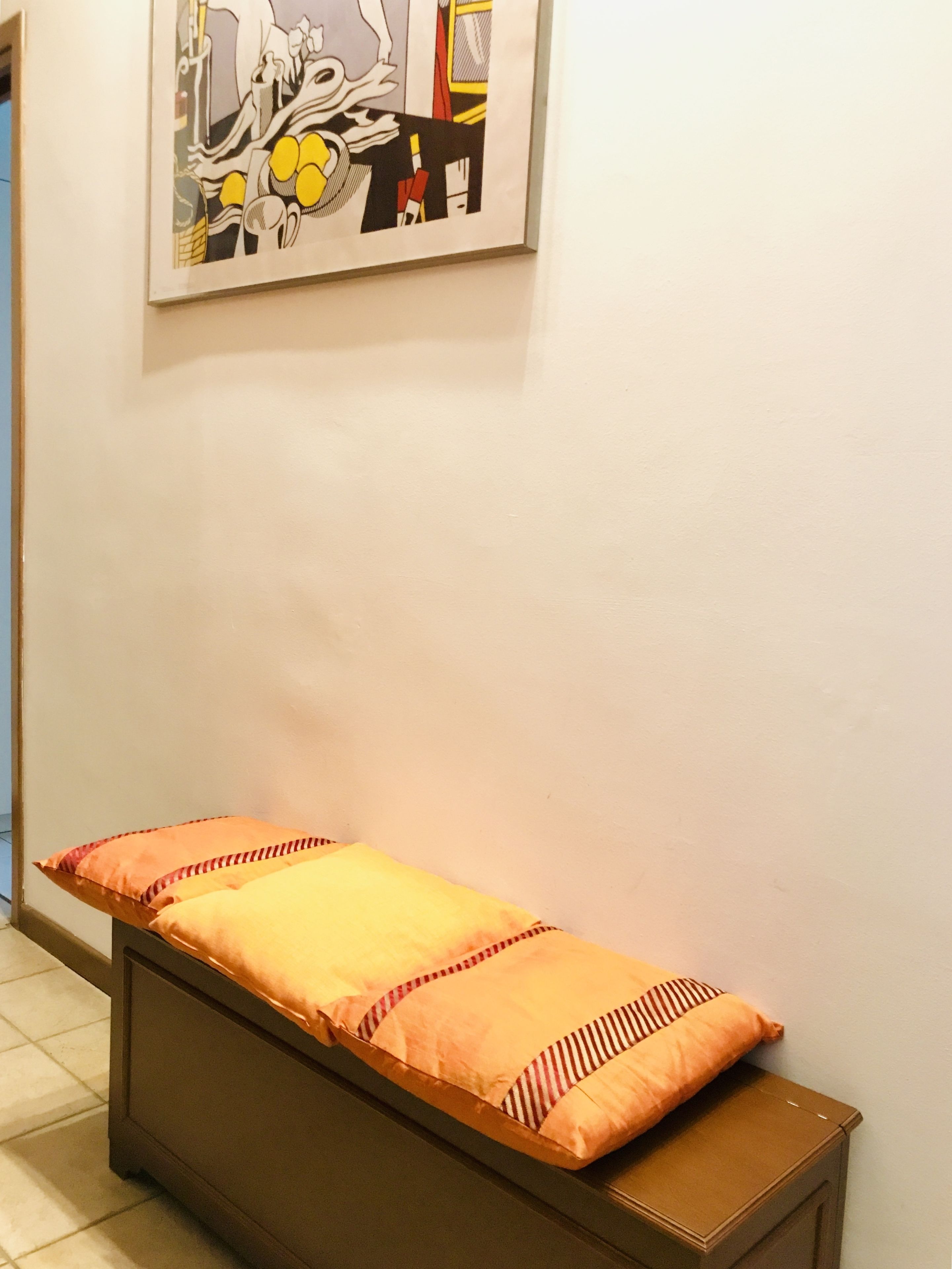 Una habitación con cama, una obra de arte enmarcada en la pared y suelo de baldosas.