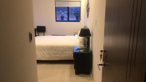 A bedroom with a bed, bedside table, lamp, and a window with a view. - Walkable to Downtown/Stadium/Hosp. St Ines. 360 View of Cuenca - Room + Terrace (Cuenca)