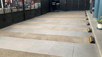 A rooftop terrace with a tiled floor, a black metal fence, and a gate leading to a building.