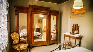 Une chambre à coucher comprenant un lit, une armoire en bois, une chaise, un bureau avec un miroir et une lampe suspendue.