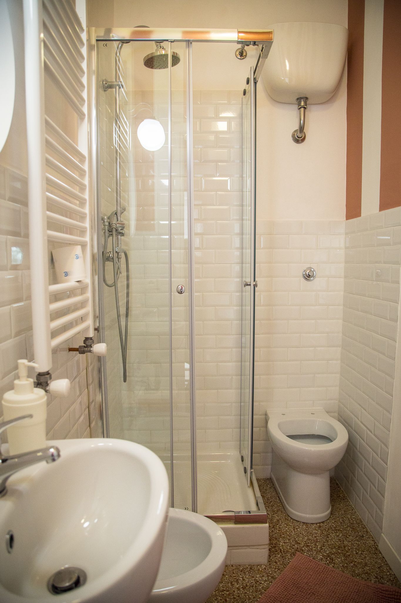 Et badeværelse med en glasafskærmet brusekabine, en hvid vask og et toilet.
