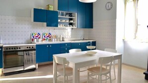 Une cuisine moderne avec des meubles bleus, une table à manger blanche et un four encastré.