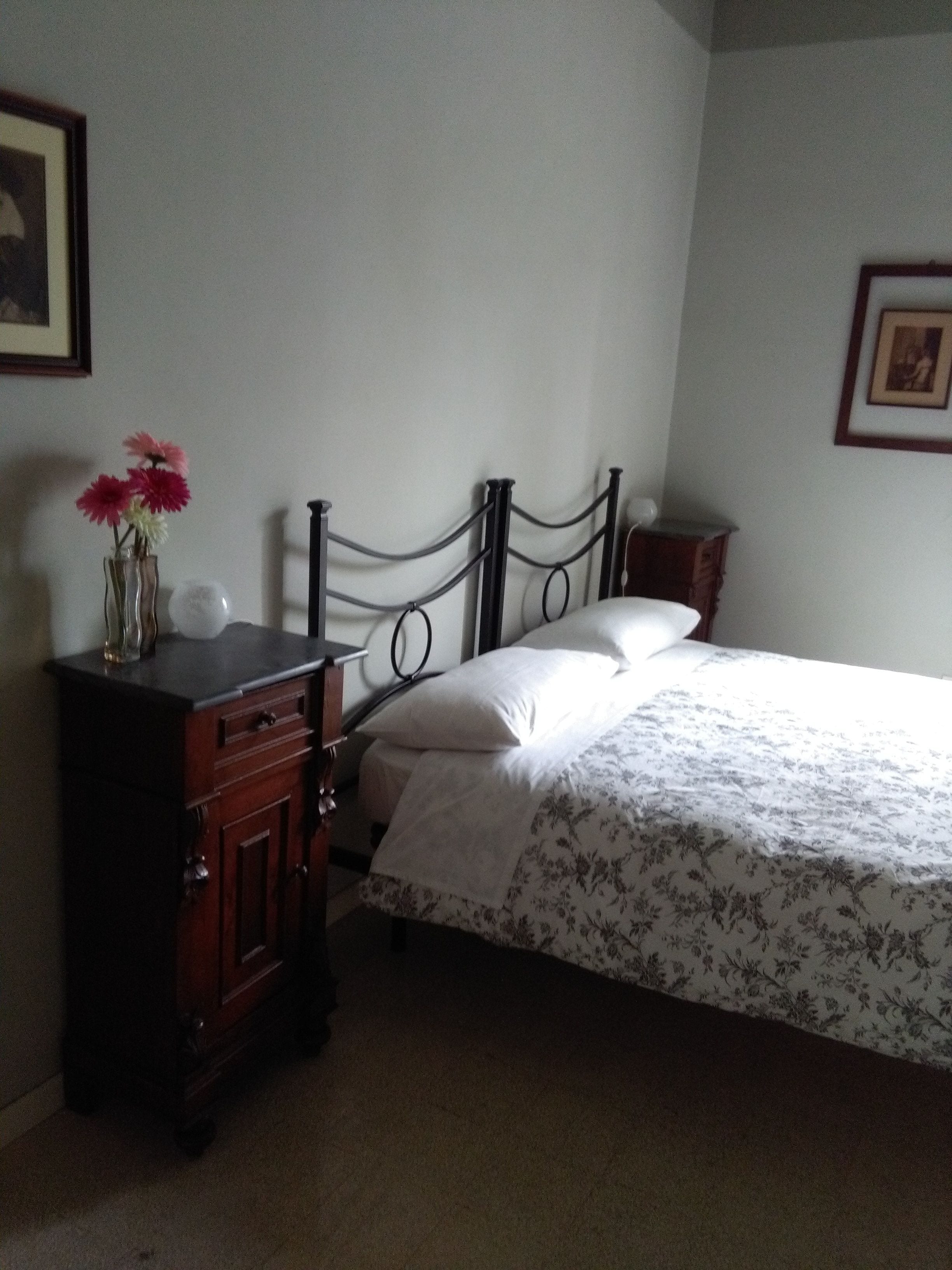 A bedroom with a bed, dresser, and a vase with flowers.