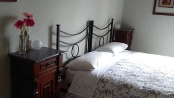 A bedroom with a bed, dresser, and a vase with flowers.